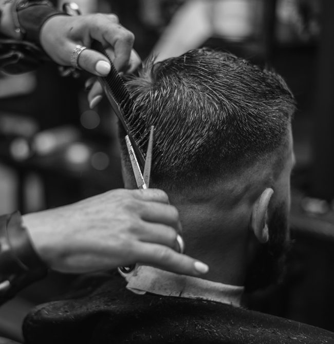 young-bearded-man-getting-haircut-by-hairdresser-BRQU2V8